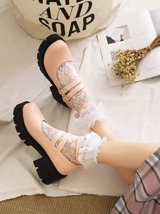 Pair of pink lolita platform pumps flat lay with frilly lace socks and home decor background showing dual buckle design