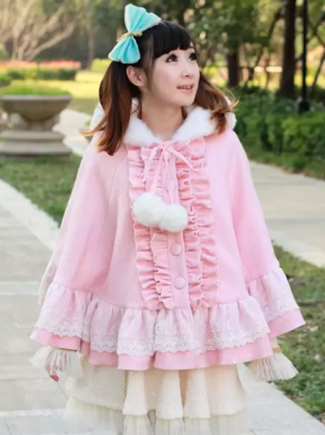 Pink sweet lolita poncho coat side profile view showing white fur collar trim and blue hair bow coordination on model against outdoor sidewalk background