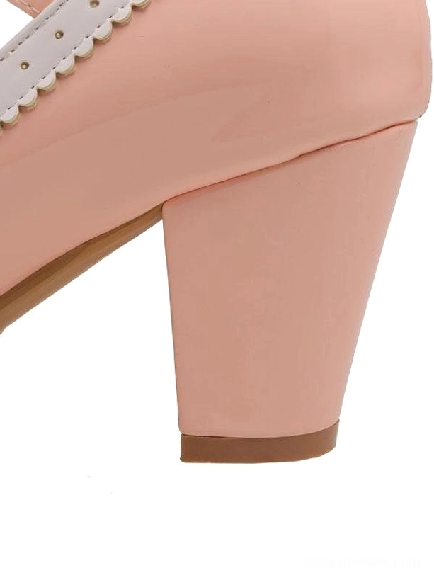 Low-angle side close-up of pink lolita pump heel showing patent leather finish and wood-toned heel bottom structural details on white background