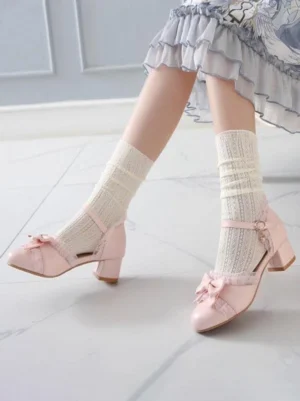 Pink PU leather Lolita chunky heel pumps with bow toe cap and adjustable ankle strap worn with ruffled Lolita skirt on marble floor