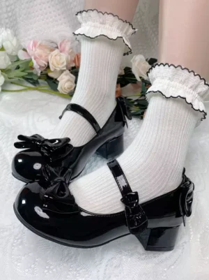Pink lolita pumps worn on model's legs with frilled white crew socks showing Mary Jane strap round toe and block heel detail