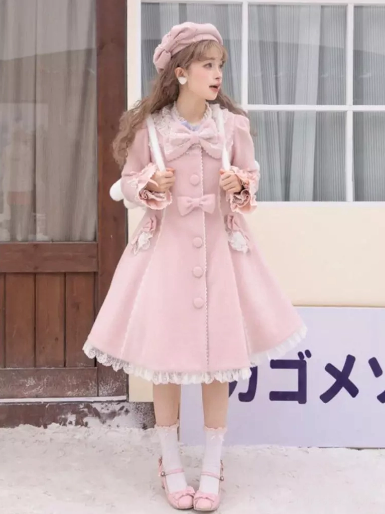 Pink sweet lolita coat side profile view on model in snowy outdoor setting, showing large neck bow, covered button placket, lace trims, and coordinated pink shoes