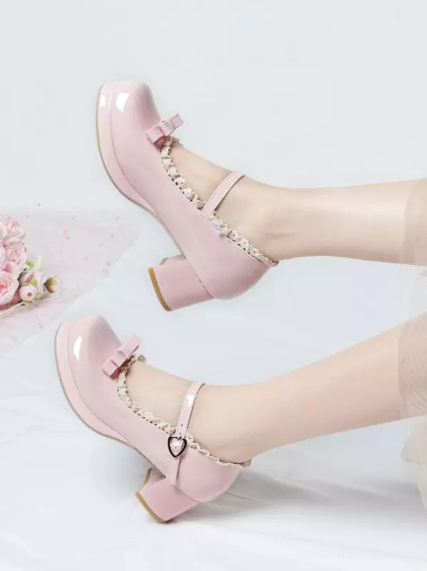 Pink patent leather lolita pumps floating feet display angle with heart-shaped buckle ruffled edge block heel indoor floral backdrop