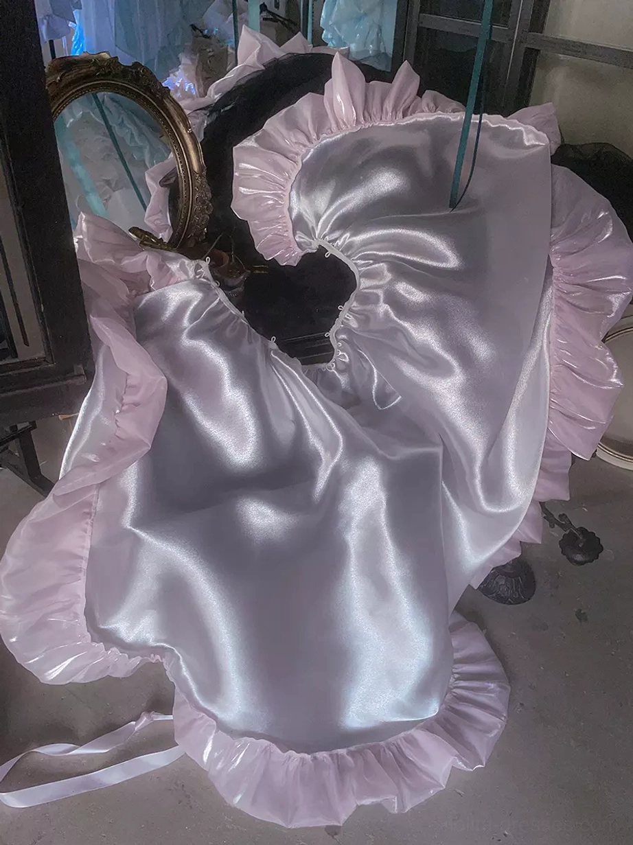 Pink ruffled ballet lolita dress fabric sample overhead close-up showing shiny silky polyester texture and ruffled edge detail