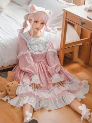 Pink polka dot sweet Lolita dress with long ruffled sleeves and doll collar, front view with cat ear headband, bedroom setting