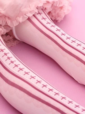Close-up side view of pink printed lolita stockings with scalloped fabric edge texture, model wearing socks against solid pink background showing geometric cross and stripe design details