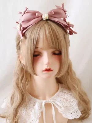 Front-facing wearing display of pink satin bow lolita headband with mini bows, cream roses and pearls, modeled on porcelain doll with delicate lace collar against pure white studio background, perfect for sweet rococo lolita fashion coordinate