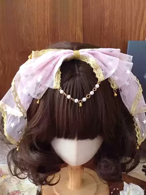 Pink star-print mesh lolita bow hair accessory with gold lace edging and pearl pendant chain on display stand