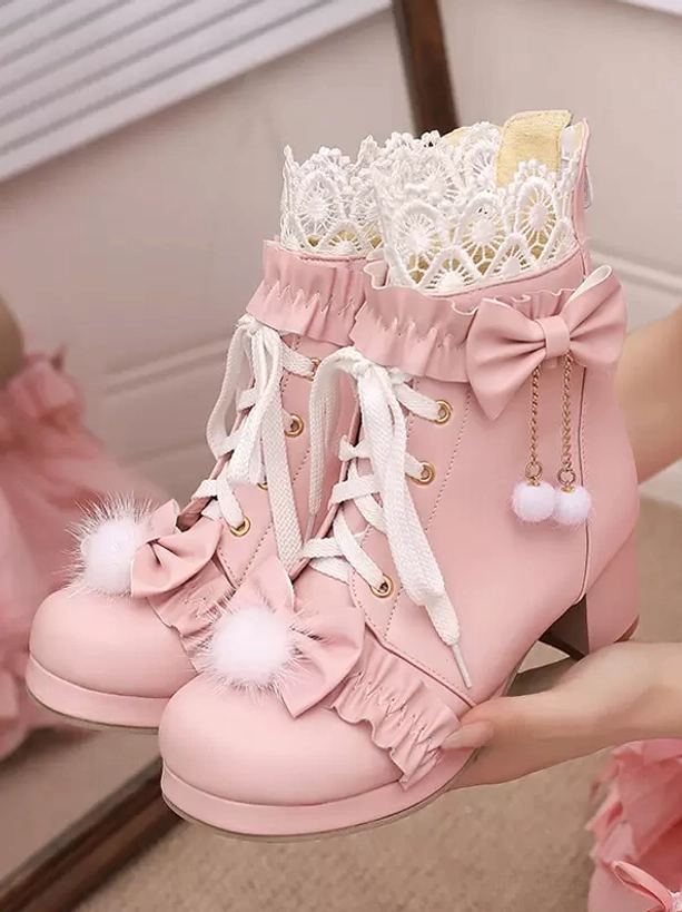 Pink lolita ankle boots pair front top view held by hand indoor room lace collar bow pendant fluffy pompom block heel design