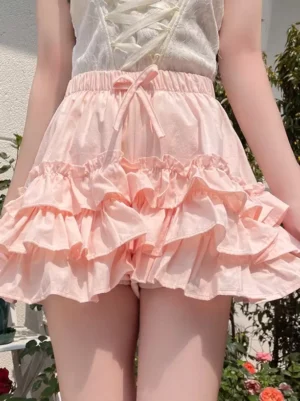 Pink sweet lolita bloomers with cascading ruffles and bow drawstring front close-up detail in outdoor garden setting