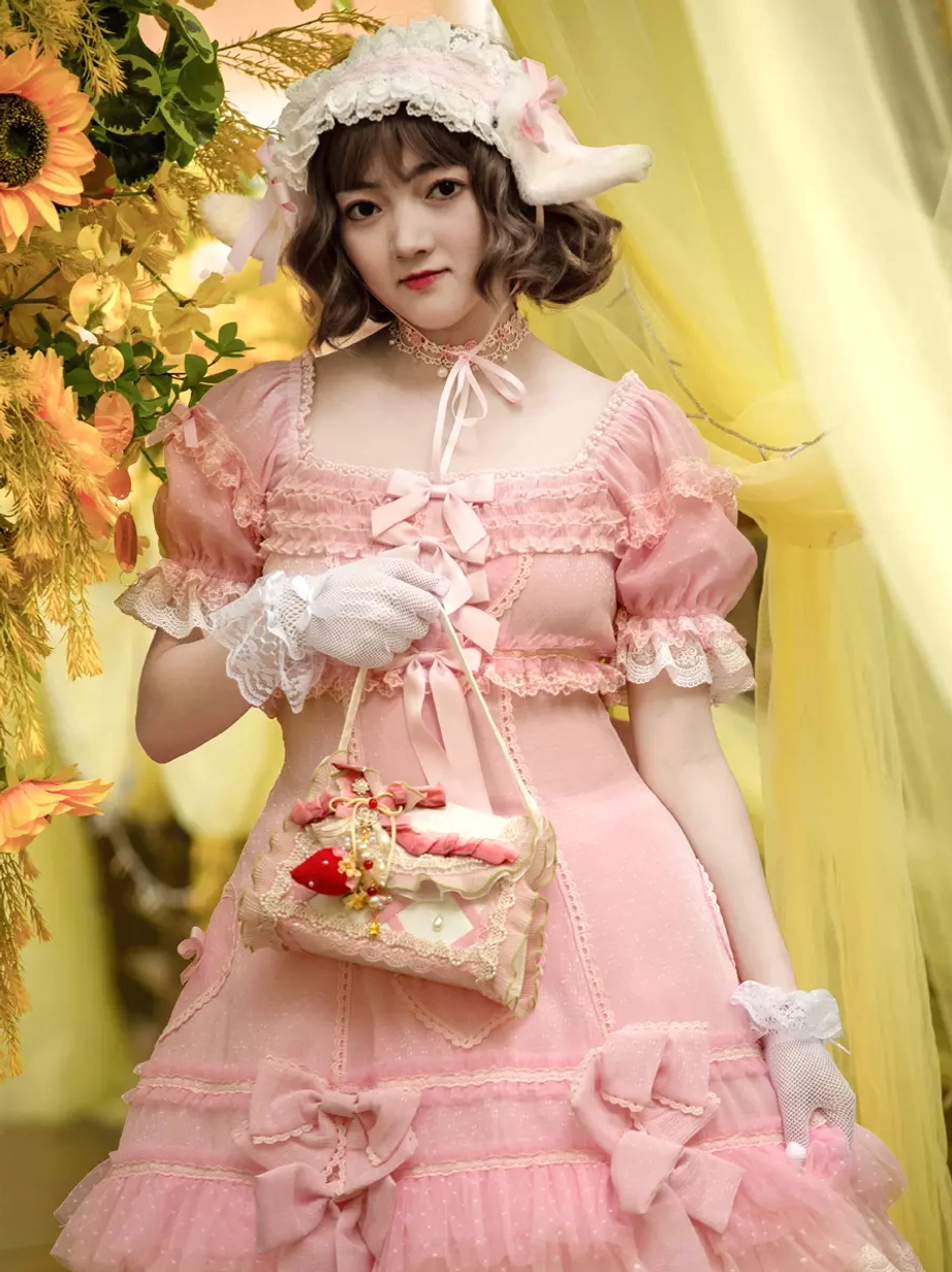 Close-up front view of pink sweet Lolita dress highlighting lace-trimmed neckline ribbon bows and puff sleeves