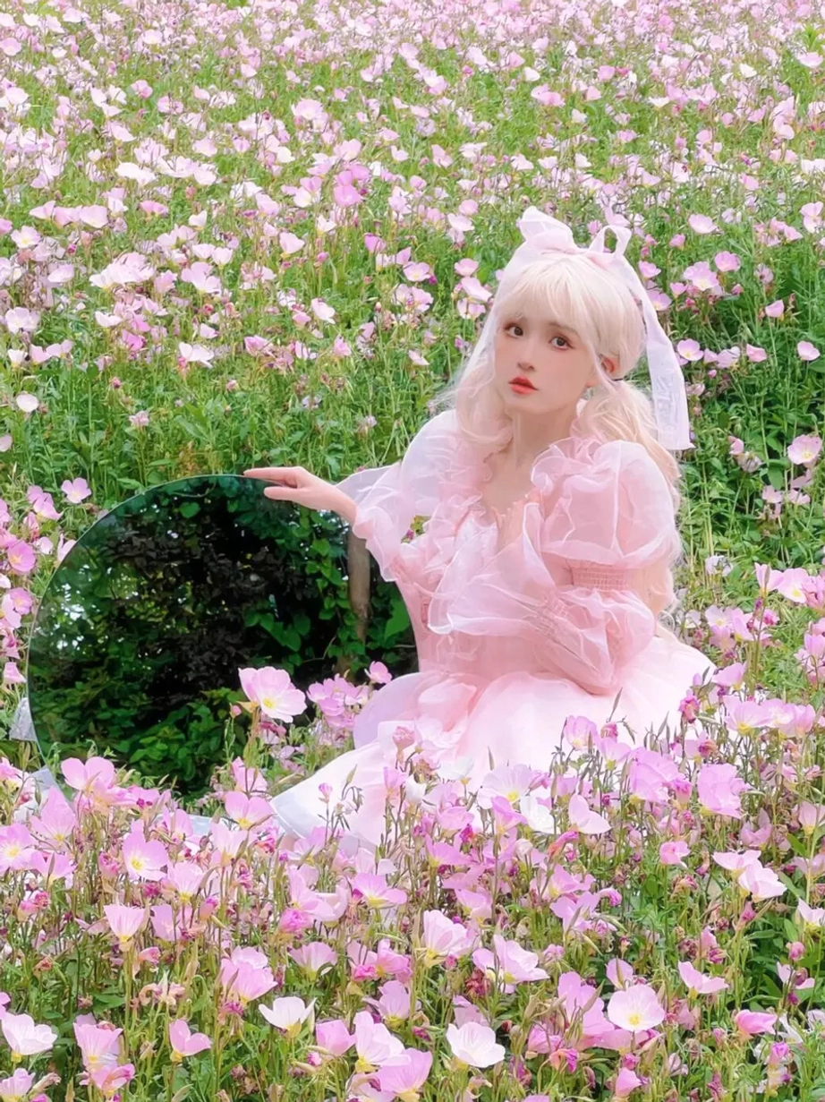 Pink sweet lolita dress side angle showcasing sheer long puff sleeves, soft flounced mini skirt layers, bow hair ornament lolita coordinate styling