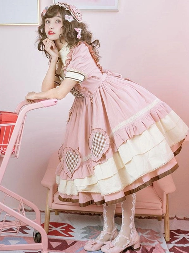 Pink sweet lolita OP dress tiered ruffled skirt side view with lace stockings and pink heels on model with curly hair