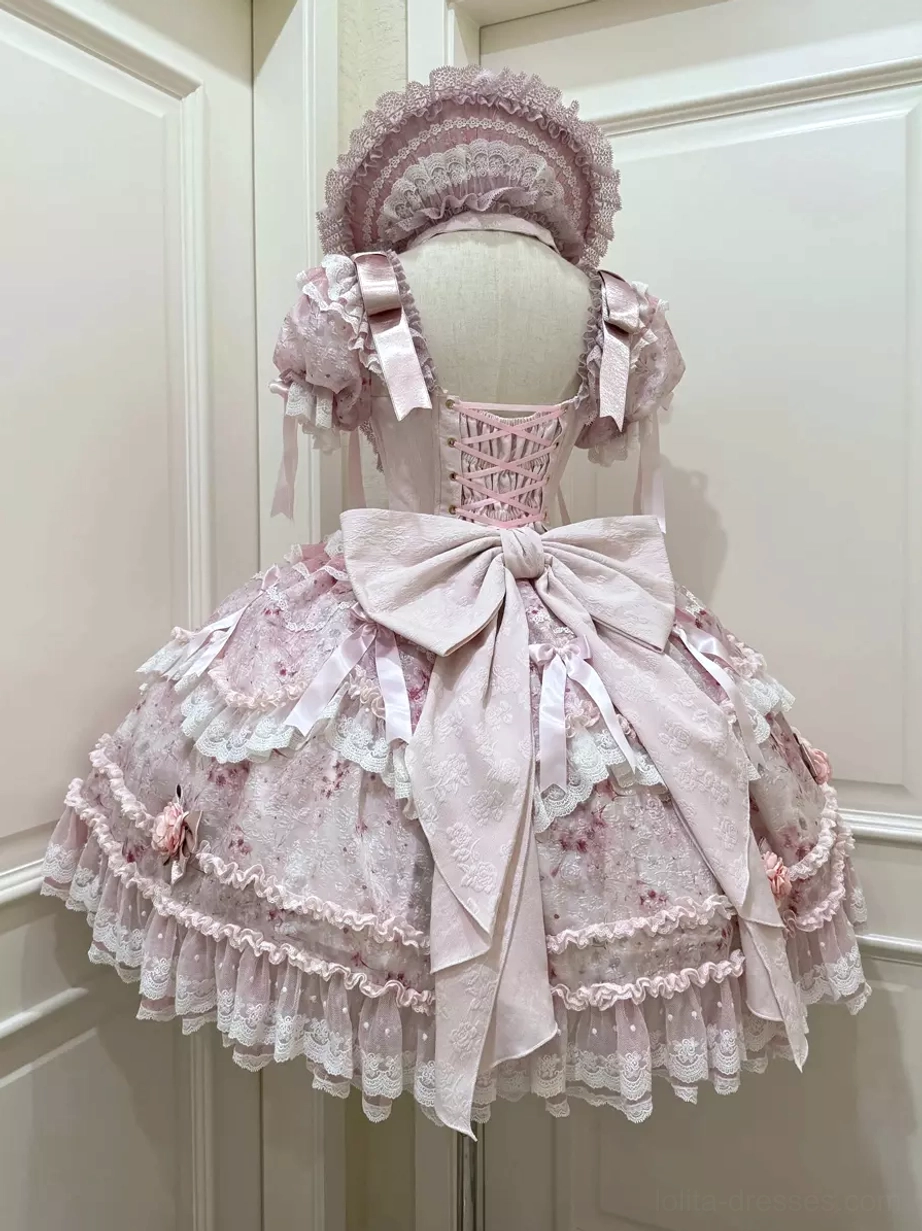 Pink sweet lolita gown back three-quarter view featuring decorative lace-up back corset construction, matching lace bonnet headwear, and coordinated ensemble details