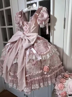 Pink sweet lolita formal gown front view showing puff lace sleeves, front lace-up bodice with V-neckline, and layered printed tulle skirt indoor doorway setting
