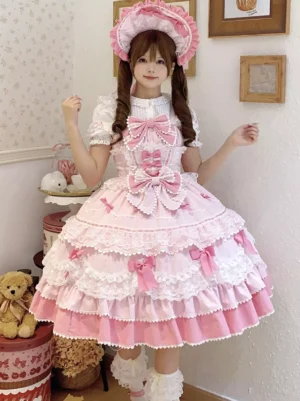 Pink sweet lolita sleeveless jumper dress with tiered lace skirt and bow details front view on model in vintage tea room setting