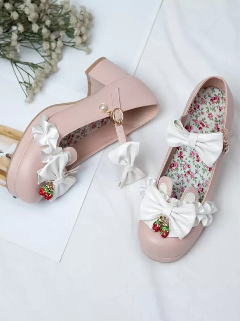Pink Sweet Lolita Mary Jane pumps flat lay styled with baby's breath flowers showing white bows, strawberry charms, floral insole, and elegant chunky heel