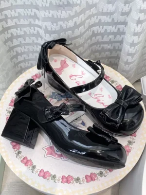 Pink sweet lolita Mary Jane pumps with bow accents displayed on floral ceramic plate flat lay view showing round toe and patent leather finish
