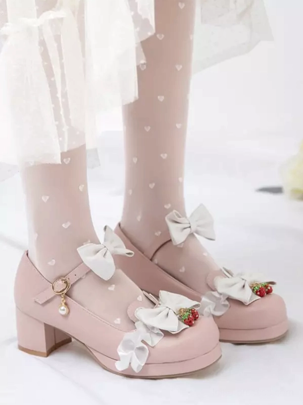 Pink Lolita Mary Jane shoes side profile displaying ankle buckle strap, white bow decorations, strawberry accents, and heart-patterned sheer stockings
