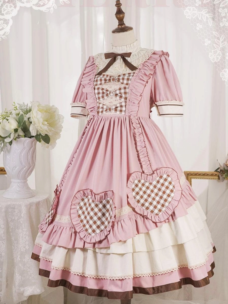 Pink sweet lolita OP dress on mannequin display showing gingham chest panel heart patches tiered ruffled hem and neck bow