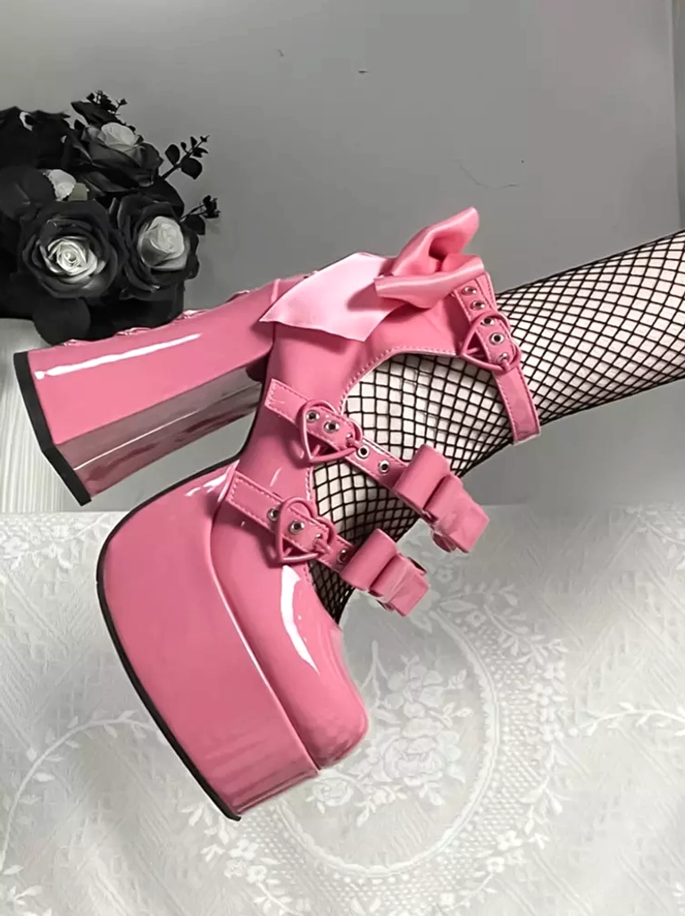 Pink sweet lolita platform pumps with large back bow and multiple buckle straps, patent leather finish, side close-up view on model wearing fishnet stockings
