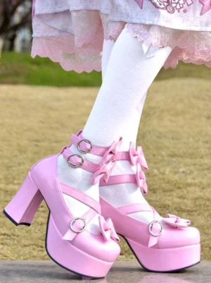 Pink Sweet Lolita platform pumps with pink patent leather bow details and chunky heel, worn with white stockings on outdoor grass, side close-up view showing ankle strap buckles and round toe