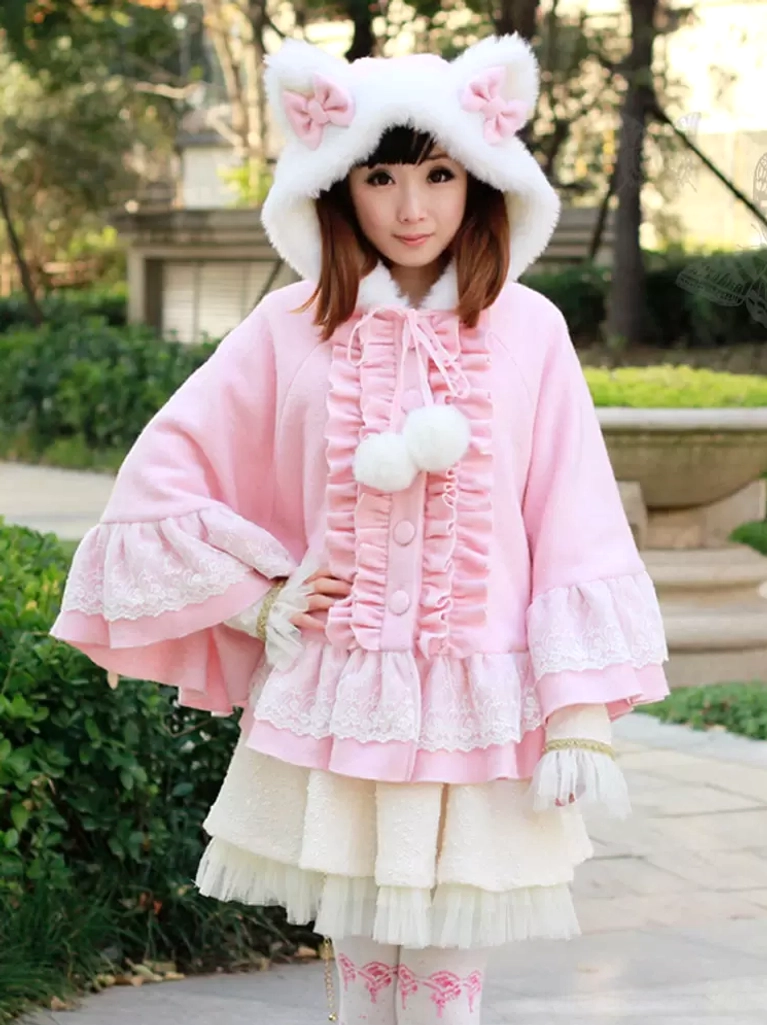 Pink sweet lolita poncho coat with cat ear hood and pink bows displayed on model in outdoor garden setting, showcasing full front silhouette and lace ruffle hem detail
