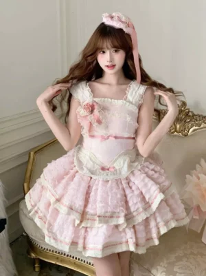 Pink tiered ruffle sweet lolita jumper dress front three-quarter view with lace trim bodice and layered skirt on model wearing pink flower hair accessory and floral brooch