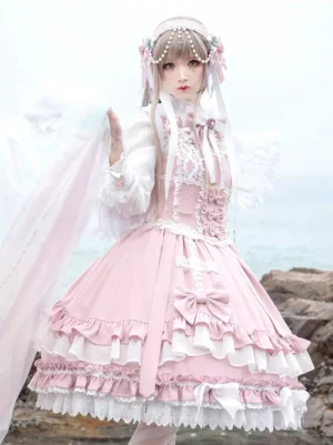 Pink sleeveless sweet lolita jumper dress with tiered ruffled lace hem and bow decorations, displayed in seaside setting with cross-style lace trims and multi-layered skirt construction