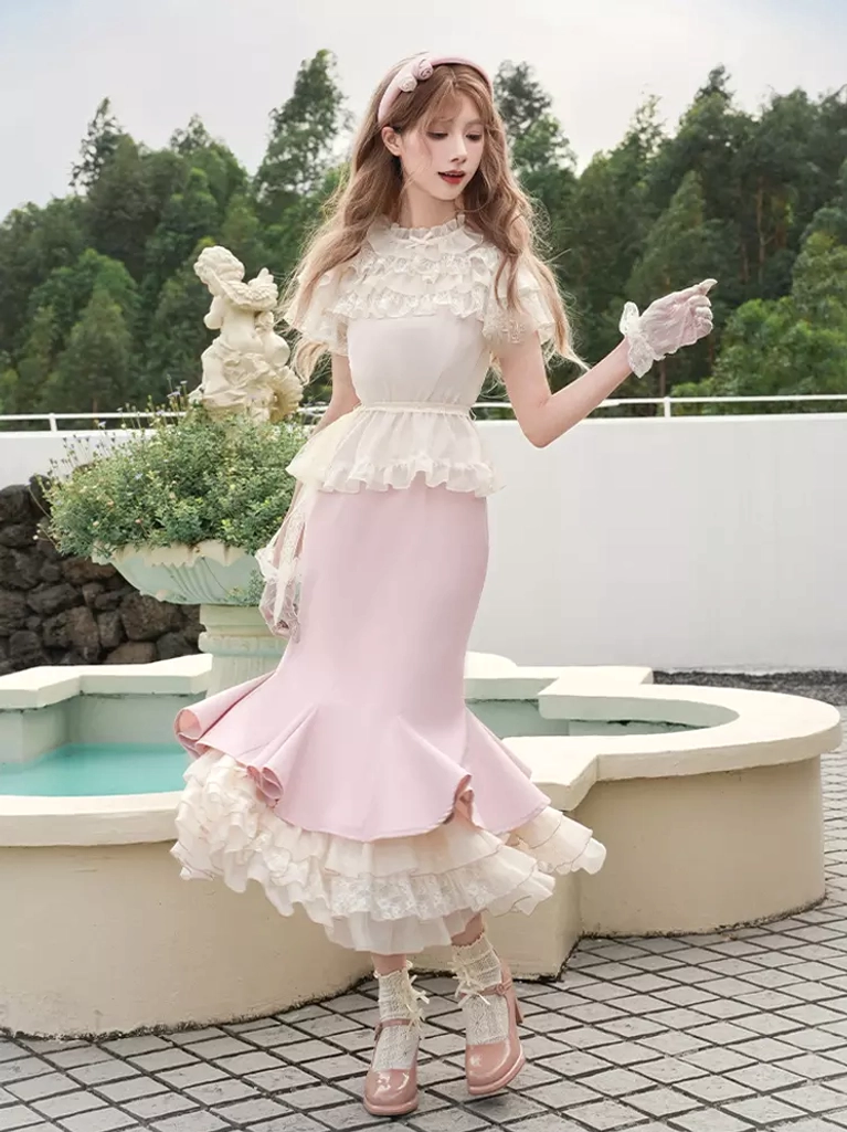 Pink sweet lolita two-piece dress set with off-white lace crop top and fishtail skirt, three-quarter front view in outdoor garden setting