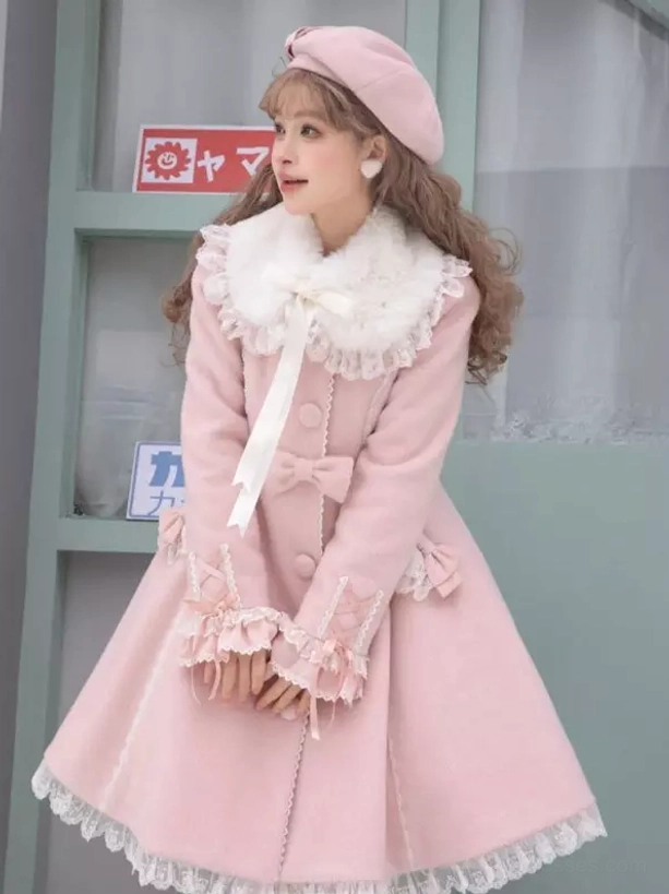 Pink sweet lolita wool coat with white faux fur collar and lace cape worn by model outdoors, showing front three-quarter view with ruffled lace trims and bow accents detail