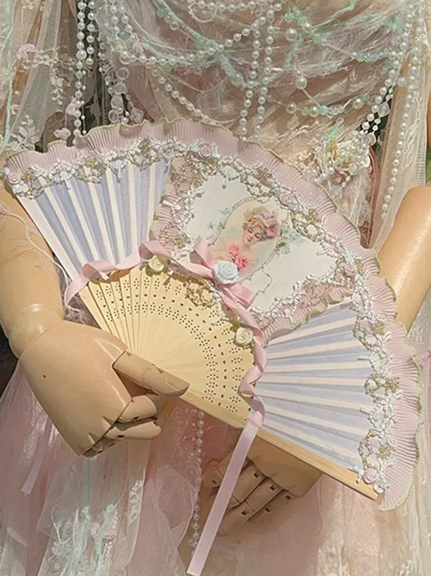 Vintage pink folding fan with classical lady portrait and delicate lace detailing displayed on wooden lolita mannequin wearing coordinating pink gown with pearl decorations and accessories, demonstrating complete coordinate aesthetic