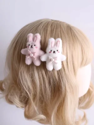 Pink and white plush bunny ear hair clips worn on blonde doll wig, rear lateral view showing fuzzy fabric texture and pearl-decorated gingham bow details for sweet lolita headdress styling