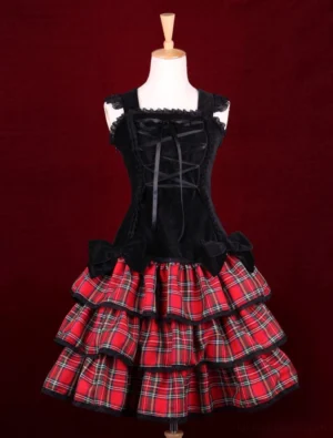 Punk Lolita jumper dress front view featuring black velvet corset bodice with lace-up front and three-tiered red tartan ruffled skirt with black lace trim, displayed on mannequin against red background