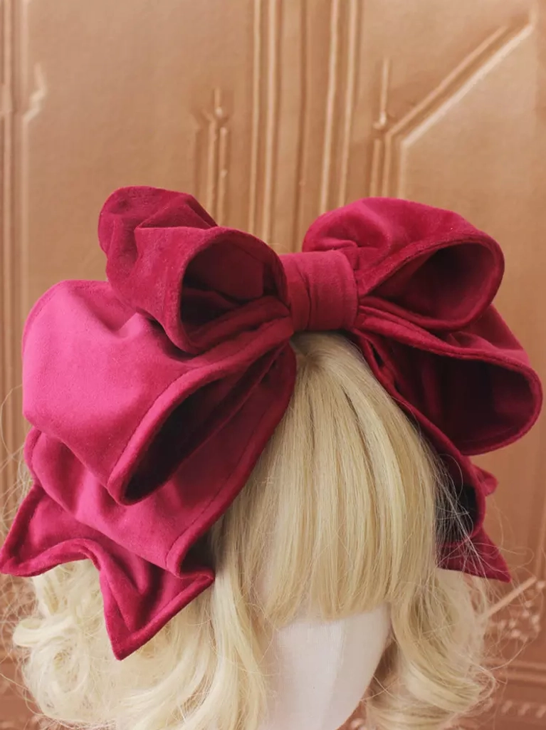 Pure black velvet Lolita bow headdress with double-layer construction displayed on brown-haired mannequin against carved wooden door, ideal for gothic-lolita and classic coordinates