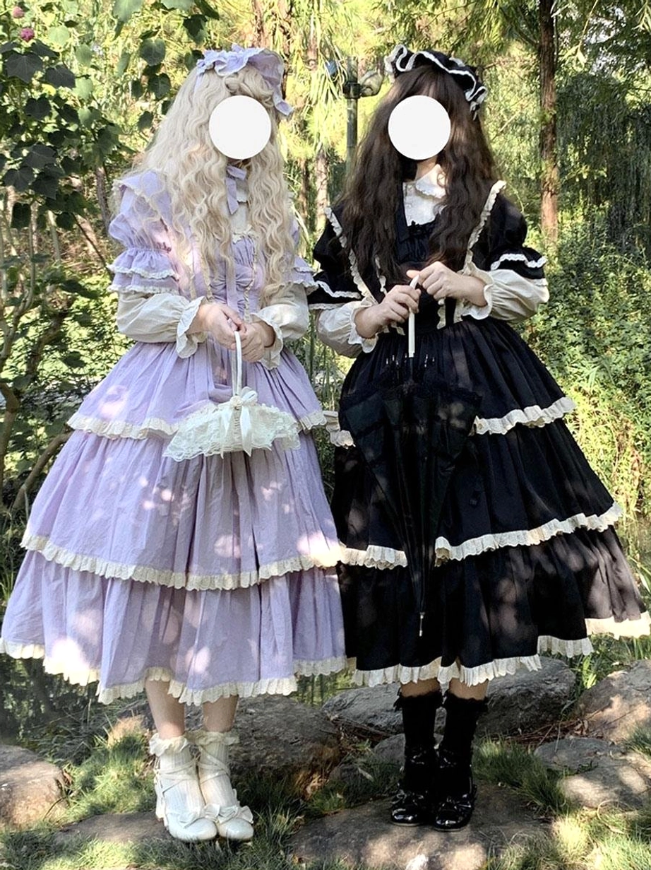 Purple gothic fairy lolita dress with tiered ruffles and white lace trim front view worn by female model in outdoor forest setting