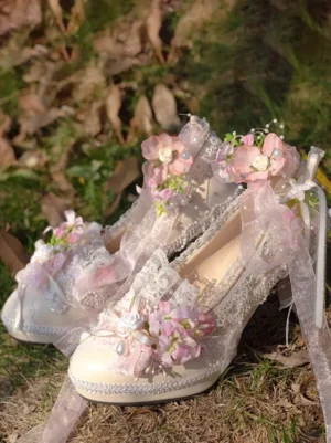 Purple and pink Lolita wedding pumps with ornate floral lace embellishments displayed on outdoor grass showing color-block design with pearl-adorned ribbon bows and delicate lace trims from overhead angle