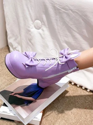 Purple lolita leather ankle boots with bow decoration and side zipper closure, shown in close-up side view on stacked books, showcasing chunky heel and lace-up details
