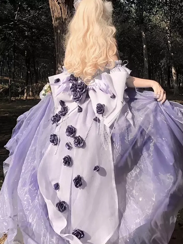 Back outdoor view of purple sweet lolita fairy dress with large statement back bow and rose appliqués showing blonde hair styling