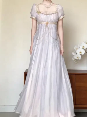 Full body front shot of lavender Lolita Regency gown with short puff sleeves, sheer wrinkled fabric, empire waist with chains, pearl necklace accessory, indoor setting
