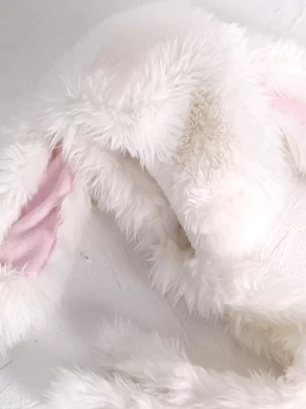 Close-up detail shot of plush white rabbit ear featuring pink inner ear lining, soft shaggy fur texture, quality construction of lolita headdress accessory