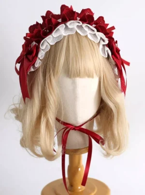 Red classic Lolita headdress with white frilled lace featuring satin bows and red fabric flowers, displayed on mannequin with blonde bangs wig, front left three-quarter view showcasing satin chin strap fastening