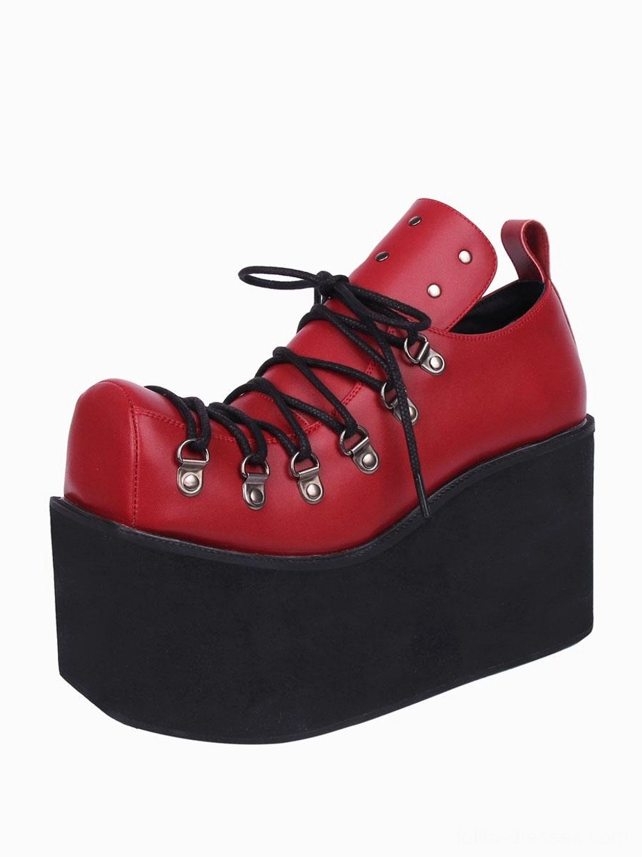 Single red gothic platform pump with ankle pull tab and silver eyelets, thick wedge platform sole, side three-quarter view in moody red colorway