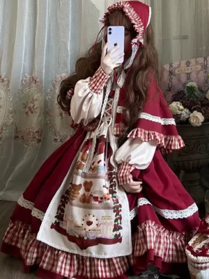 Red plaid sweet lolita dress with hooded cape front three-quarter view worn by model taking selfie with gingham trim details and dessert-themed apron print