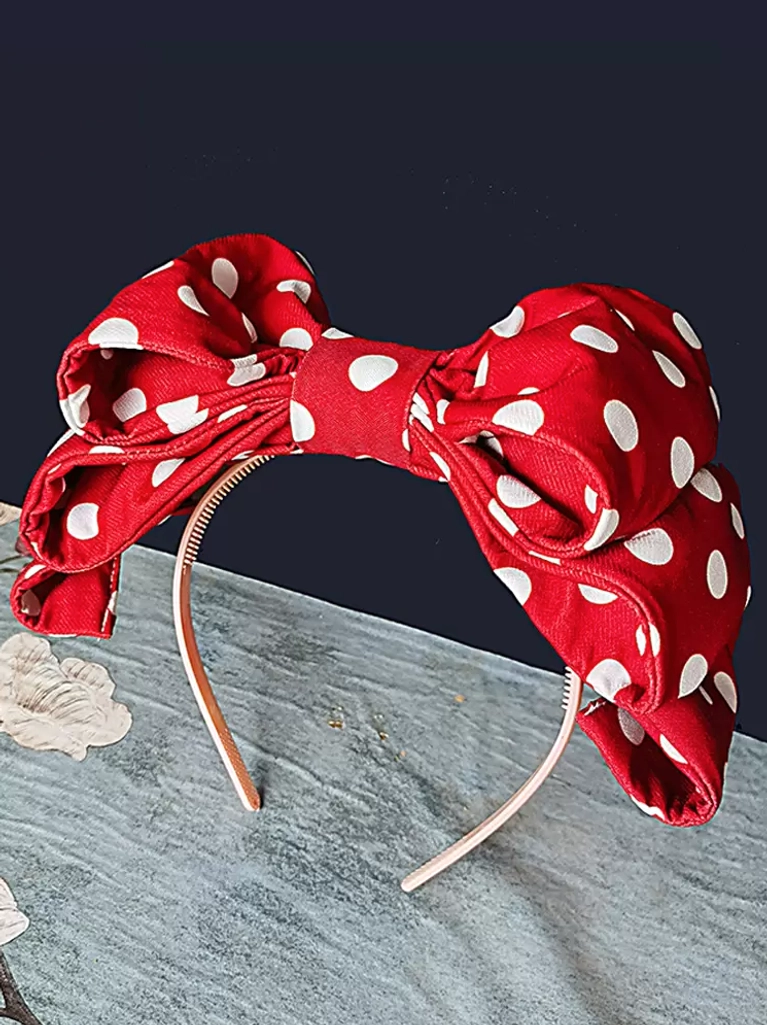 Red polka dot lolita headband flat lay side view showing plastic headband base and padded bow construction