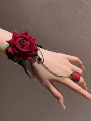 Flat lay overhead shot of red flocked rose hand chain jewelry set showing black lace wristband, antique bronze chains and black beads detail, vintage gothic aesthetic