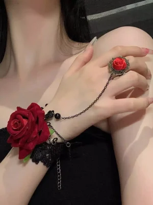 Red rose gothic hand chain bracelet with black lace and antique bronze chain worn on model wrist, matching rose ring detail, close-up side view