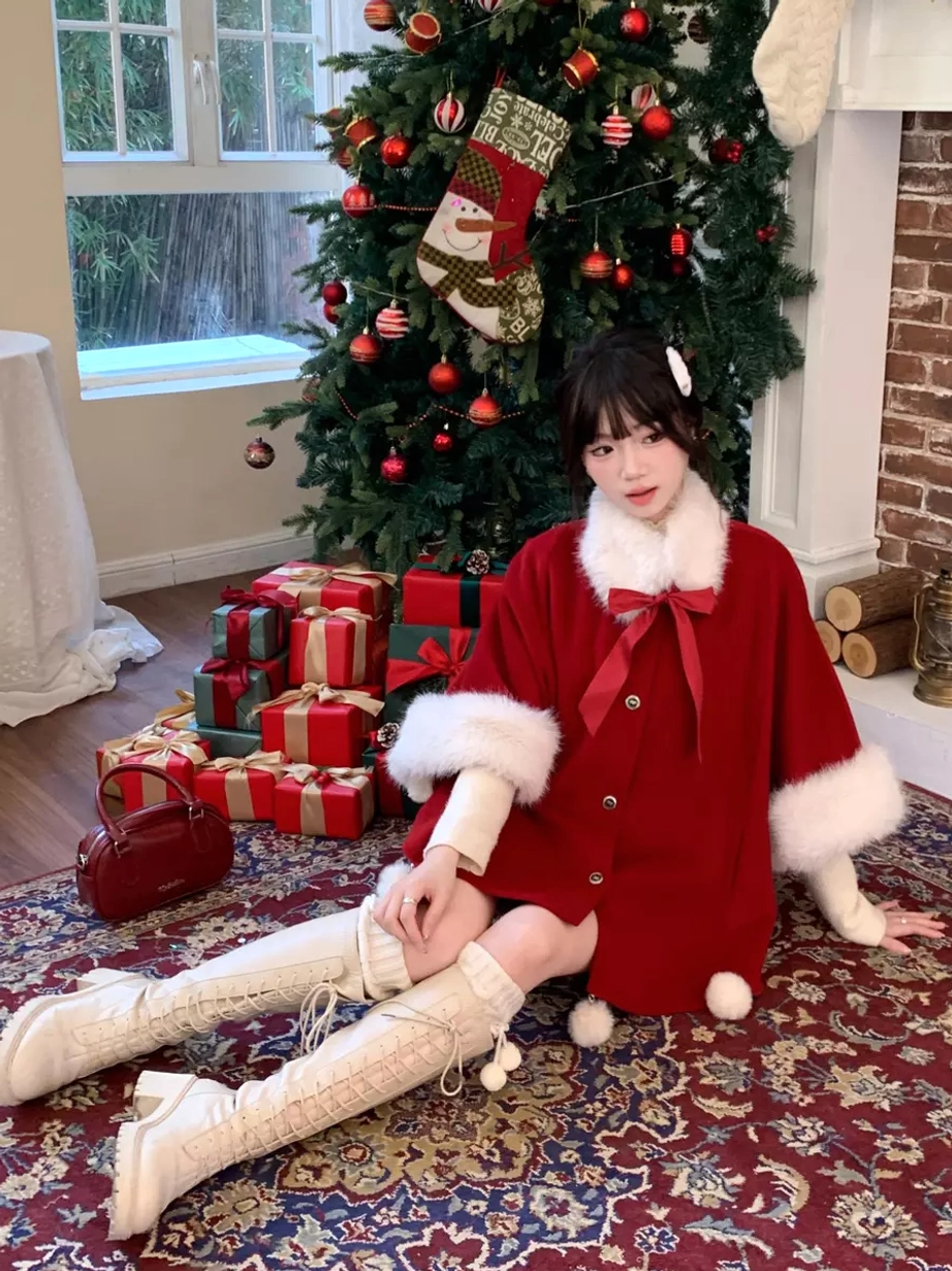 Red Sweet Lolita Christmas cape coat low front angle view model sitting on floor white knee-high boots hem pom pom decorations next to Christmas tree