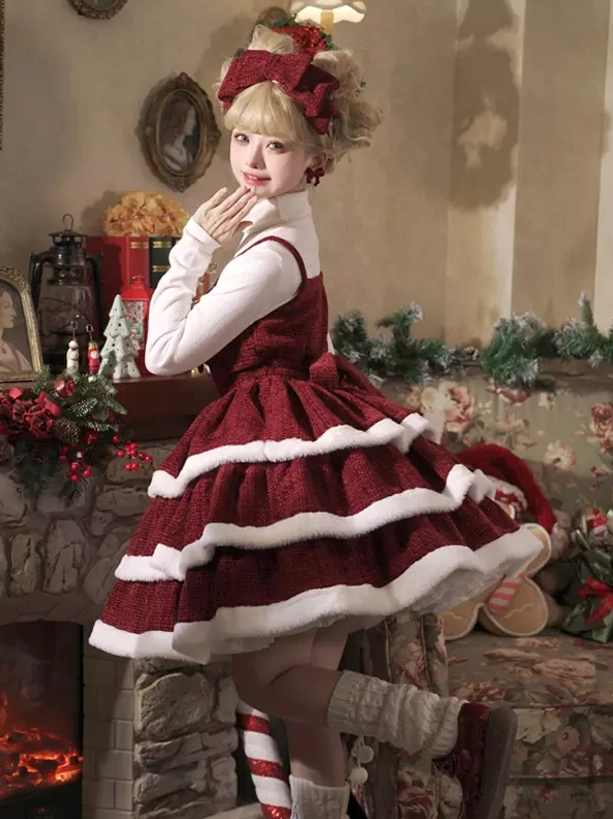 Back three-quarter shot of red sweet lolita Christmas dress cape showing tiered ruffle skirt construction and striped knee socks stone fireplace background