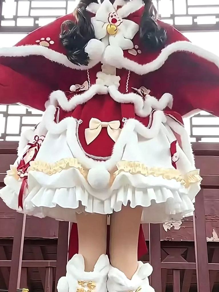 Back partial view of red Sweet Lolita Christmas hooded cape set worn outdoors showing cat ear-shaped hood, ruffled white skirt, gold embroidered furry leg warmers in traditional setting